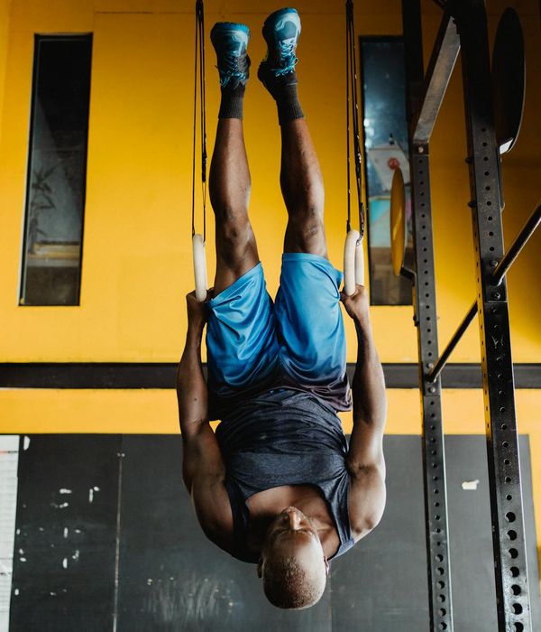 Man performing a controlled strength exercise in a modern, dark gym.